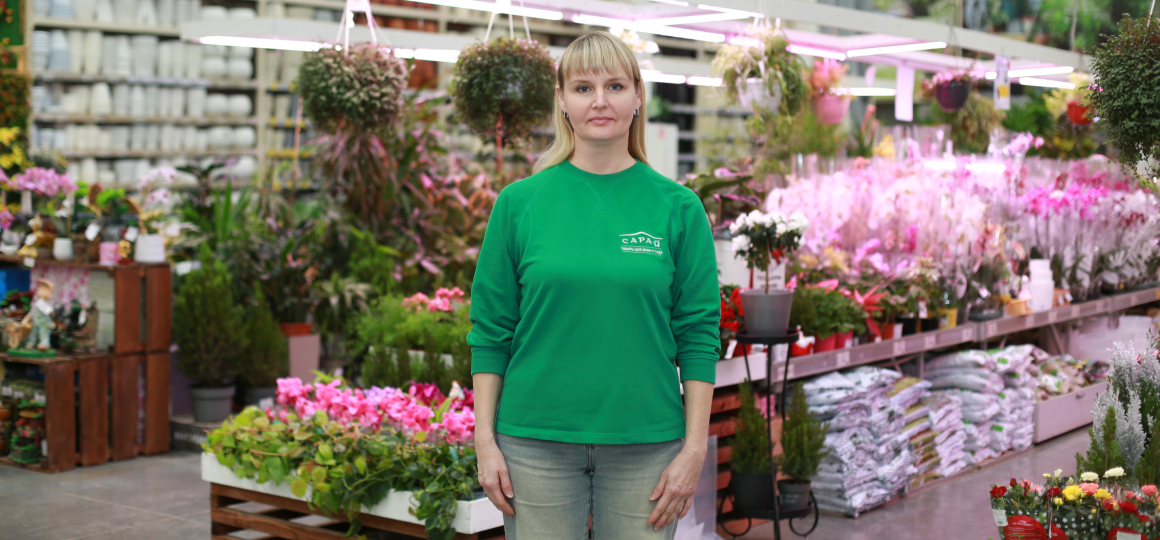 сотрудник магазина сарай в садовом отделе среди комнатных растений и цветов под фитолампами