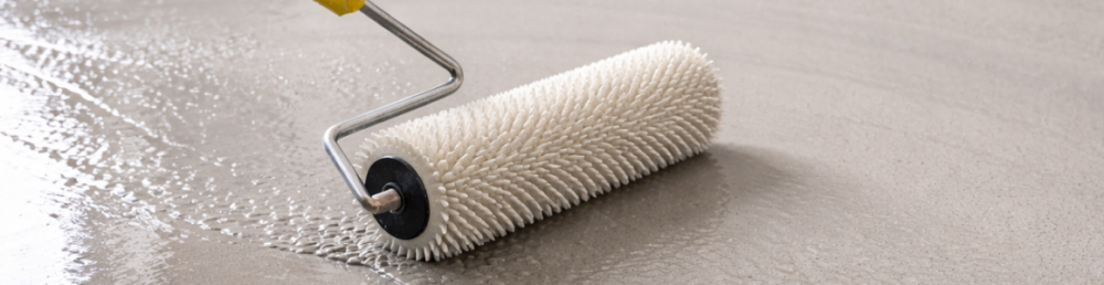 Прокатка свежего наливного пола игольчатым валиком для удаления воздуха и выравнивания поверхности