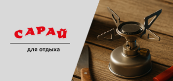 Туристический стол с мини газовой плиткой, баллоном, картой, ножом, компасом и котелком на фоне деревянной поверхности при мягком дневном освещении
