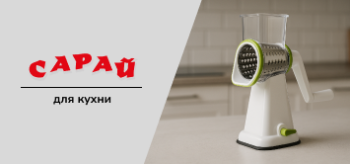 Ручная роторная тёрка на светлой кухонной столешнице с нейтральным фоном. Модель с прозрачным контейнером и металлическим барабаном, без продуктов.