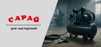 Ременной компрессор большого объёма в индустриальном цеху, на полу рядом — пневмоинструмент и шланг, в фоне — промышленное оборудование.