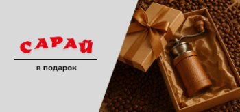 Открытая подарочная коробка с ручной кофемолкой на фоне рассыпанных кофейных зёрен