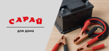 Автомобильный аккумулятор и провода для прикуривания с медными зажимами на деревянной поверхности