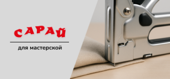 Металлический механический степлер прижат к толстой ткани на деревянной поверхности, показан момент пробивки скобой