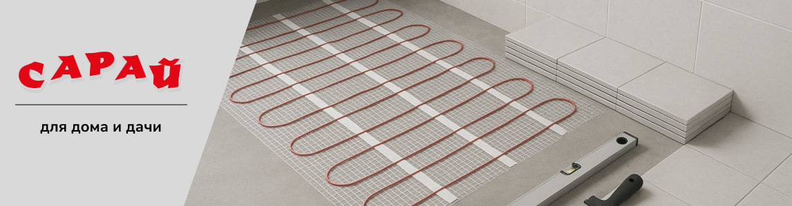 Фрагмент ванной комнаты в процессе ремонта, на полу разложен рулонный кабельный тёплый пол, рядом плитка, уровень и шпатель