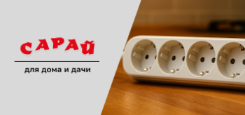 Белый удлинитель с четырьмя розетками, тремя USB-портами и включённым выключателем с подсветкой, стоит на деревянной столешнице кухни